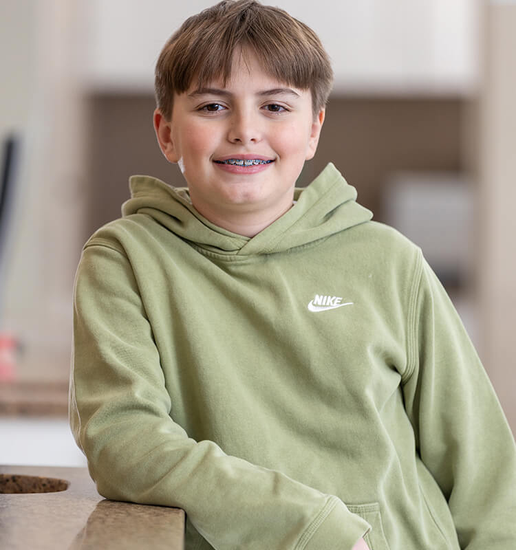 Clear Aligners, smiling boy with braces in a green hoodie