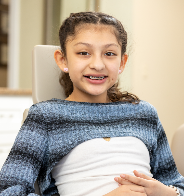Smiling girl with braces sitting in a dental chair