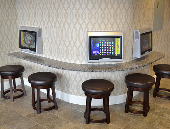 Gurnee, video game station with three arcade screens and leather bar stools at a granite counter