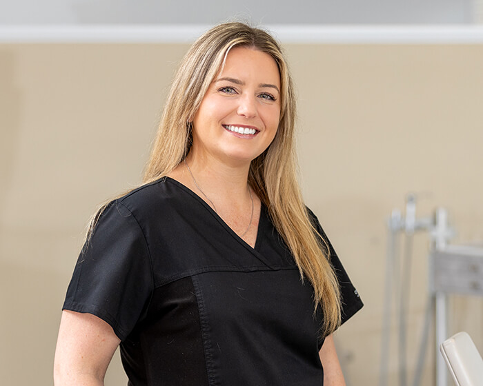 Smiling woman in black scrubs at a dental office