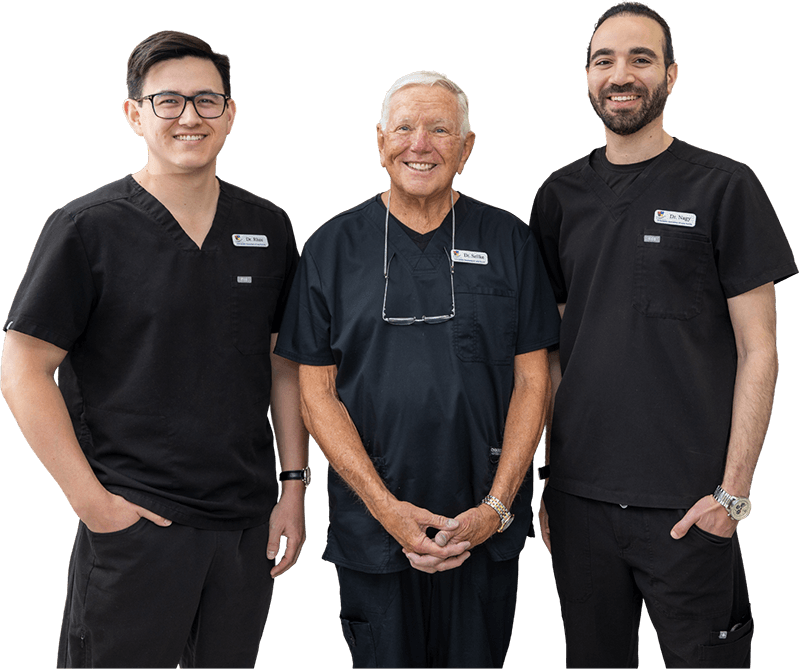 Three smiling dentists in black scrubs standing together
